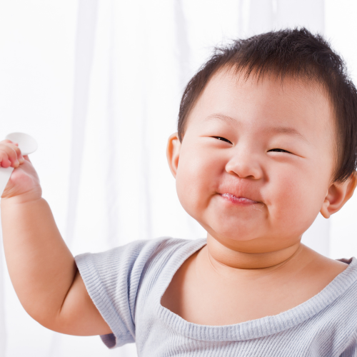 A messy faced baby eating food happily.